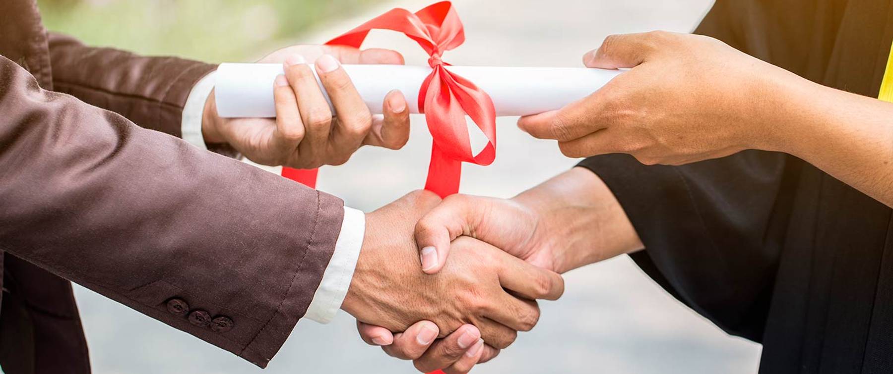 Una ceremonia de graduación donde se entrega un diploma y se estrechan manos.