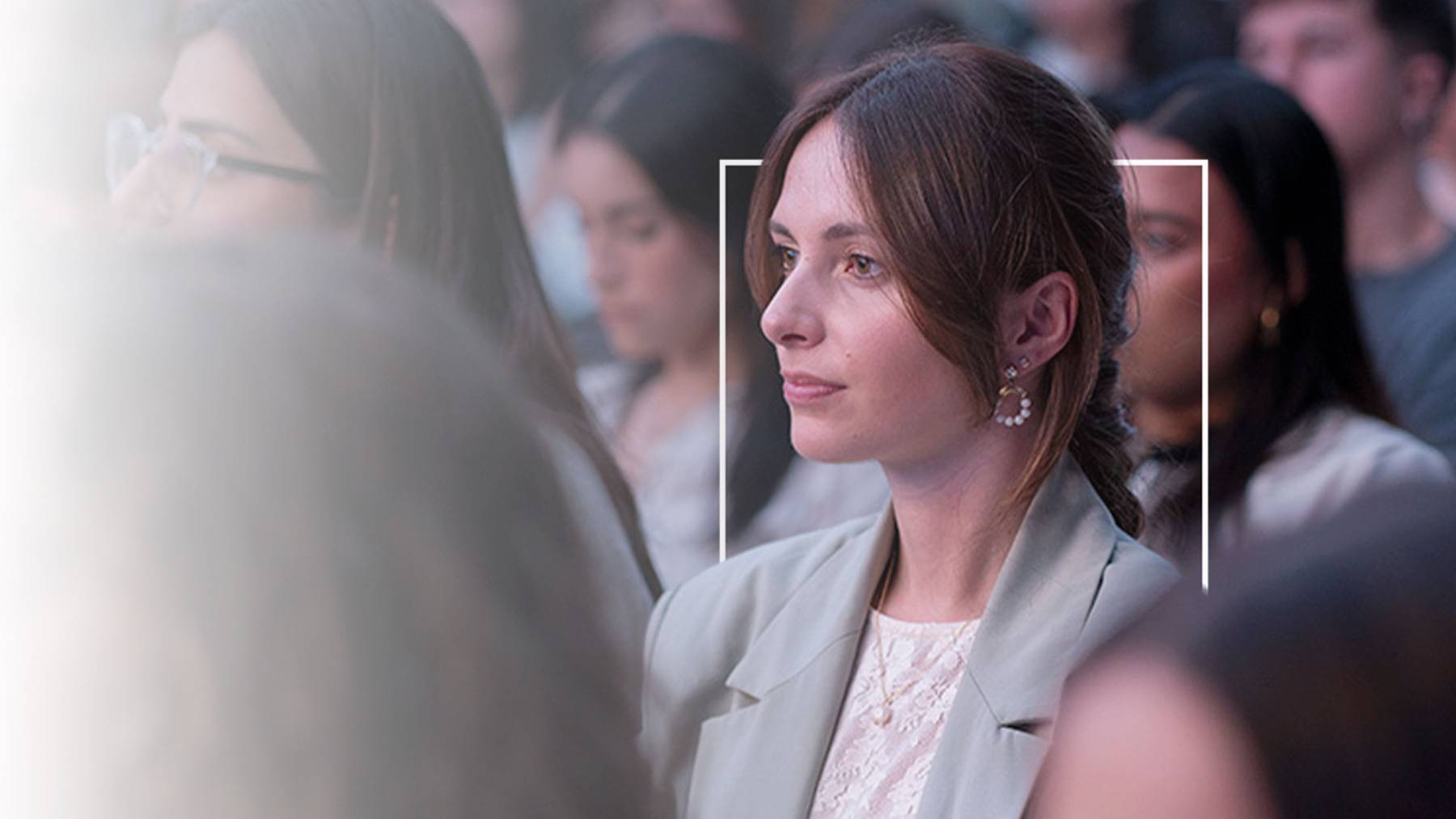 Una mujer observa atentamente en un evento rodeada de otras personas.