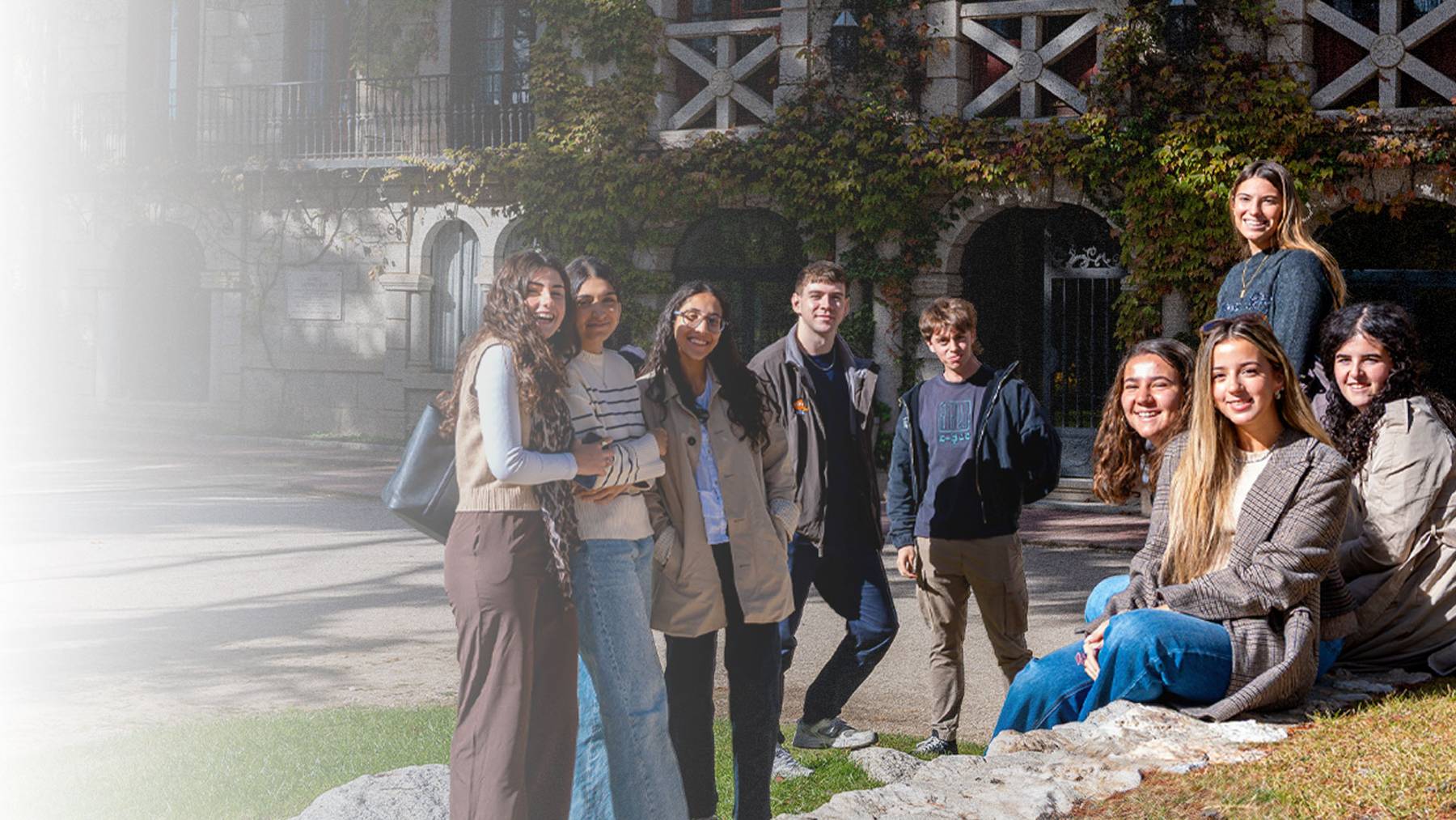 Un grupo de jóvenes posando juntos en un ambiente exterior con un edificio de fondo.