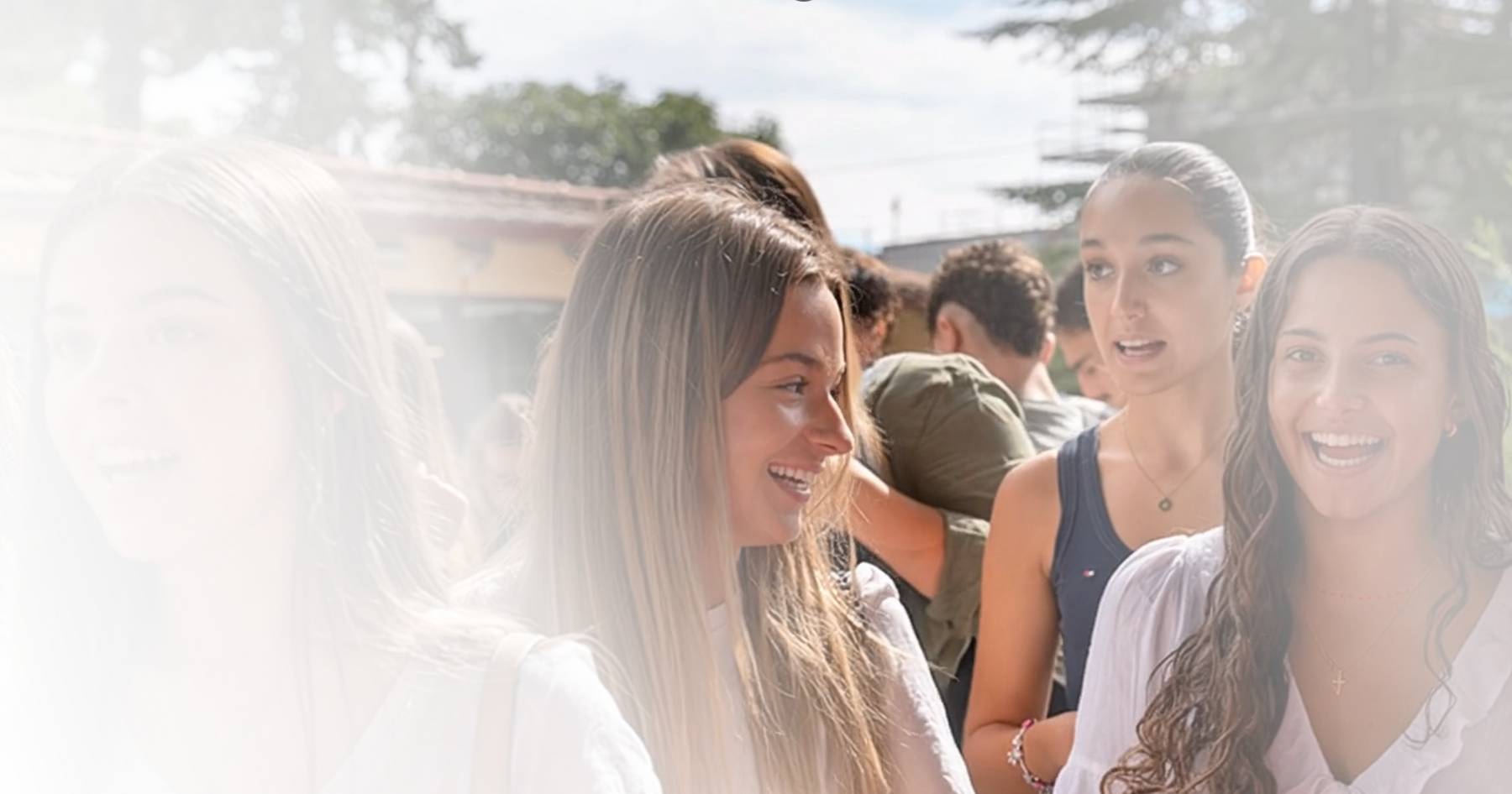 Un grupo de jóvenes sonriendo y conversando al aire libre en un ambiente cálido y soleado.