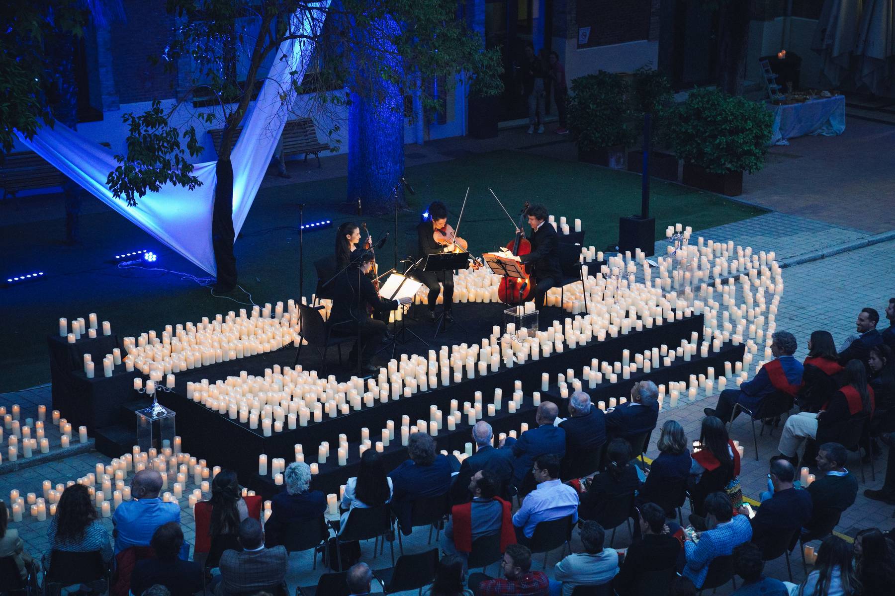 Un cuarteto de música actúa rodeado de velas en un ambiente íntimo y iluminado suavemente.