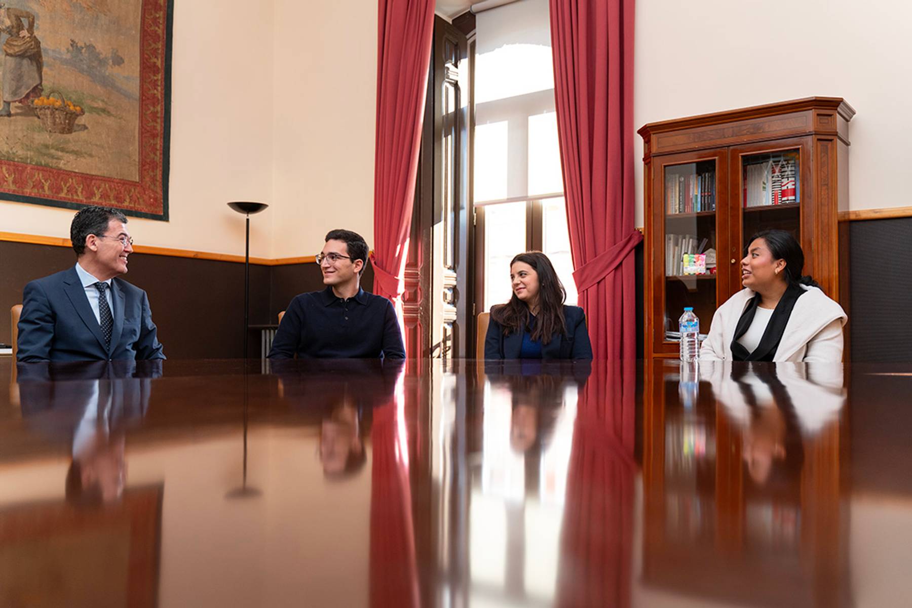 Cuatro personas se reunieron alrededor de una mesa en un ambiente formal.