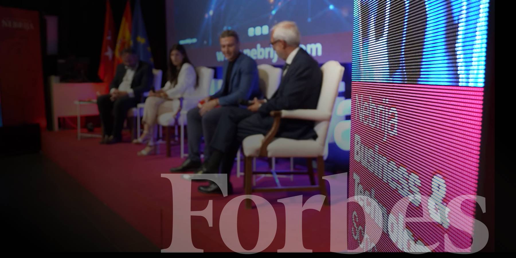 Un panel de discusión en un evento con varias personas sentadas en un escenario.