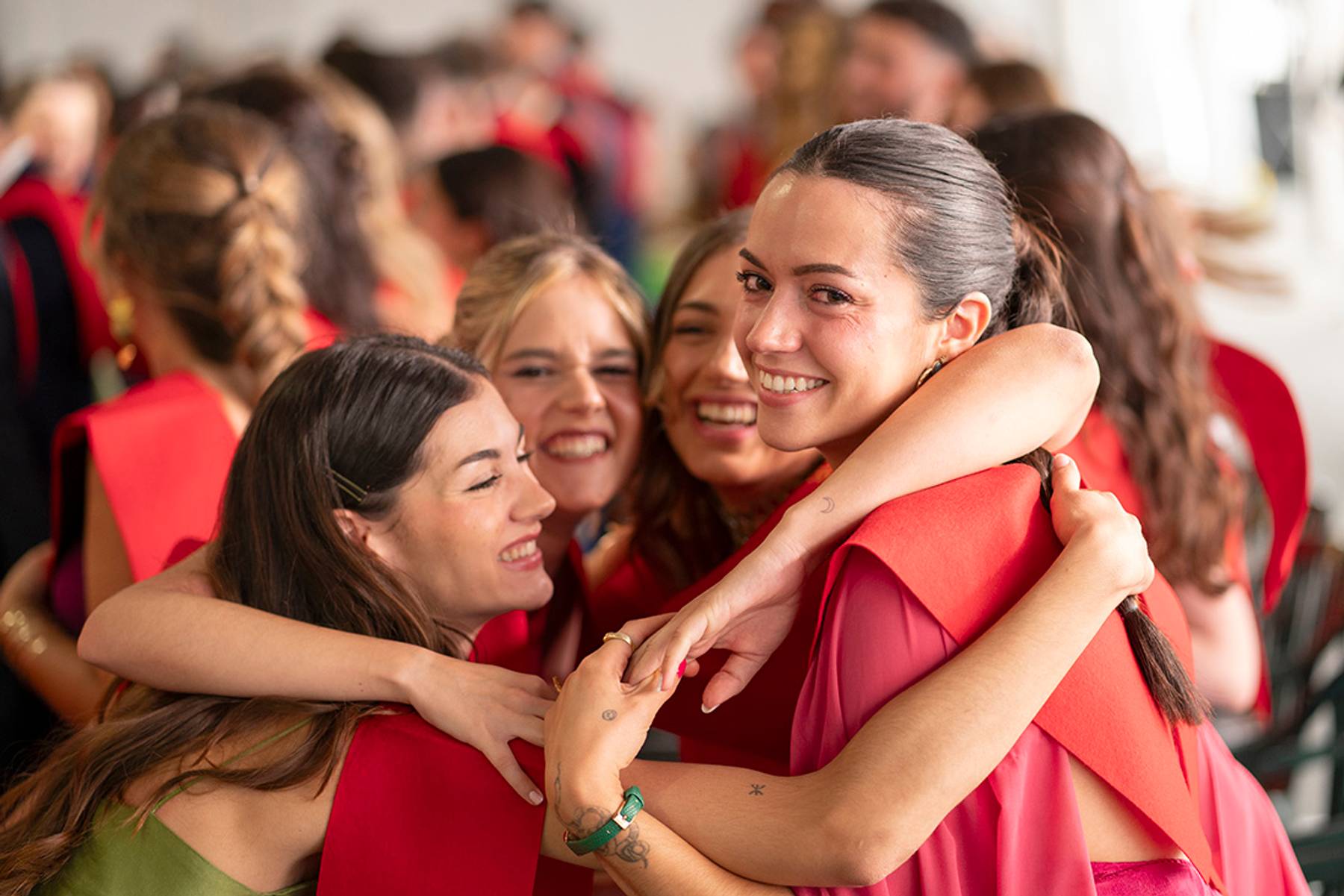 Un grupo de amigas se abraza y sonríe durante una celebración de graduación.