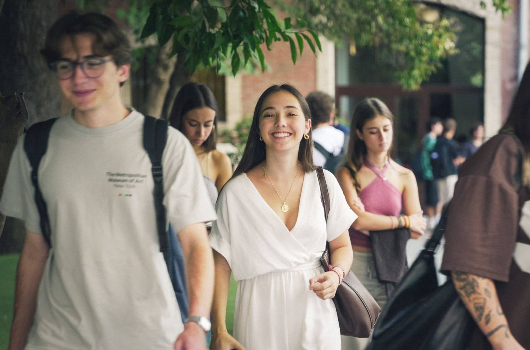 Un grupo de jóvenes camina juntos por un entorno urbano, mostrando sonrisas y buena energía.