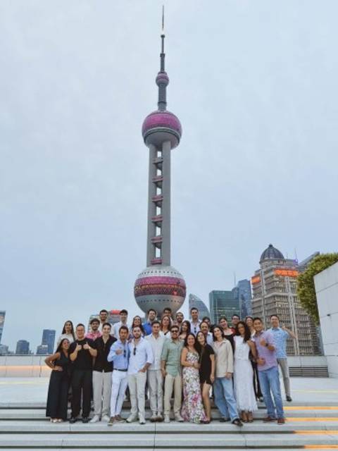 Un grupo grande de personas posa frente a la Torre Perla Oriental en Shanghái, China.
