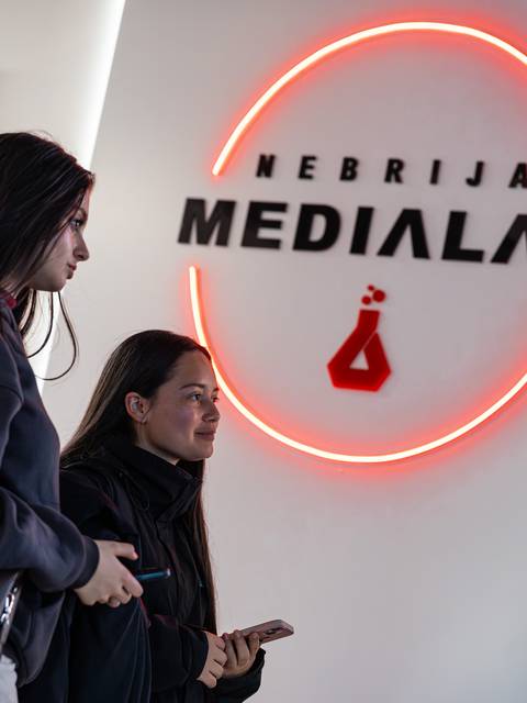 Dos jóvenes están en un espacio con el letrero de MEDIALAB Nebrija iluminado.