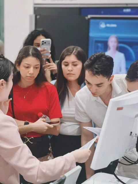 Un grupo de jóvenes se reúne alrededor de una computadora en un ambiente de atención al cliente.