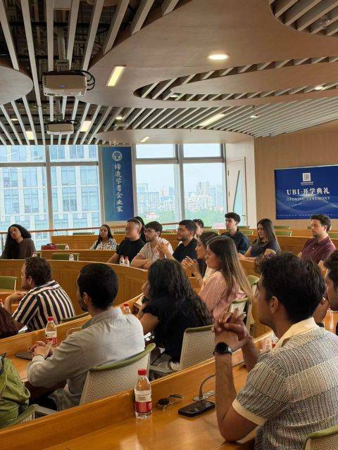 Un grupo de personas sentadas en un aula, prestando atención a una presentación.
