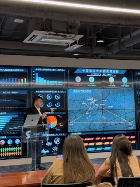 Un presentador muestra datos en una pantalla grande durante una conferencia en un entorno moderno.