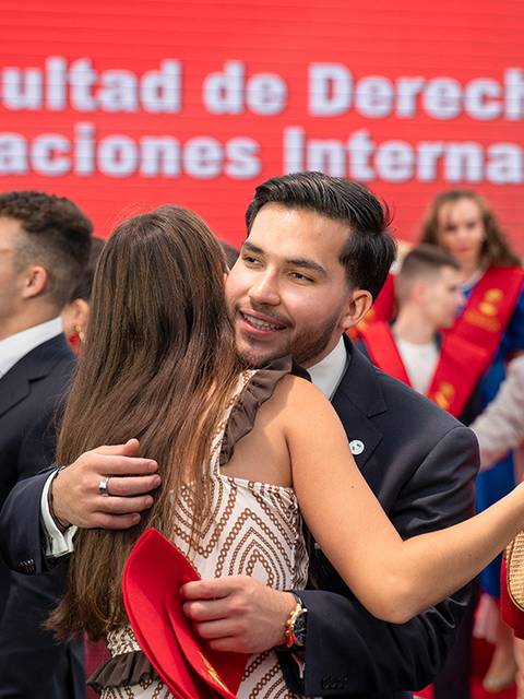 Una celebración de graduación en la Facultad de Derecho y Relaciones Internacionales donde los estudiantes se abrazan y posan felices.