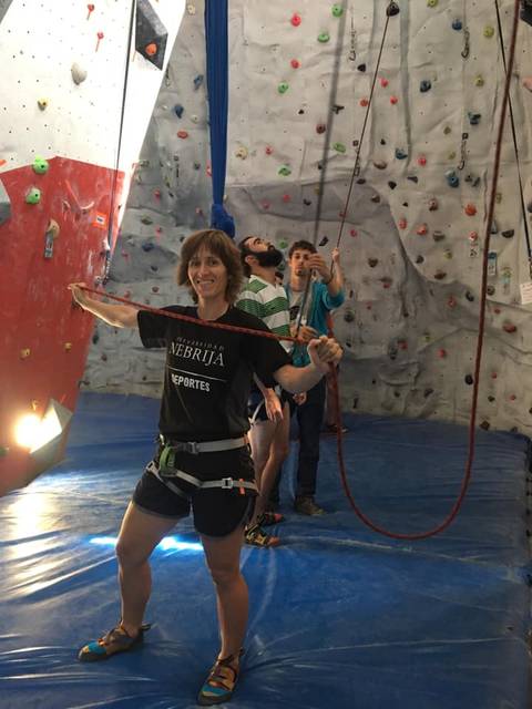 Un grupo de personas se prepara para escalar en un rocódromo indoor.