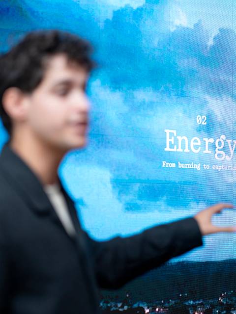 Un joven señala una pantalla que muestra información sobre la energía y la contaminación.