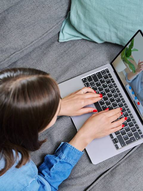 Una persona usando una computadora portátil mientras videochatea con otra persona en la pantalla.