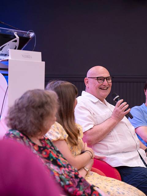 Un grupo de personas sentadas en un panel, compartiendo risas y conversaciones durante un evento.