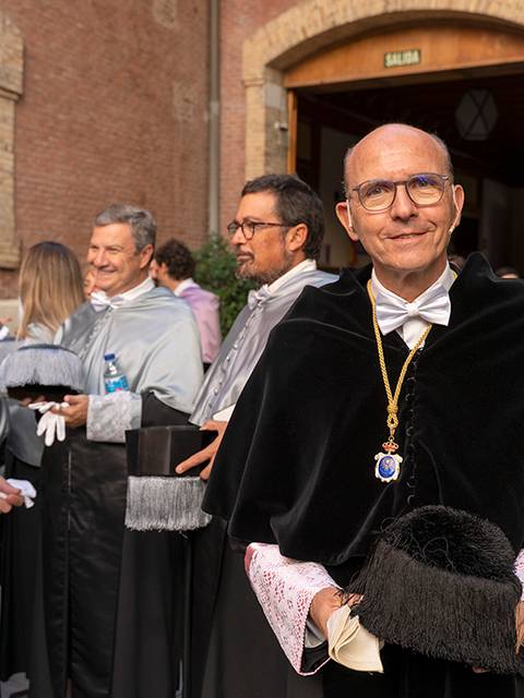 Un grupo de personas vestidas con togas académicas se reúne en un evento formal al aire libre.