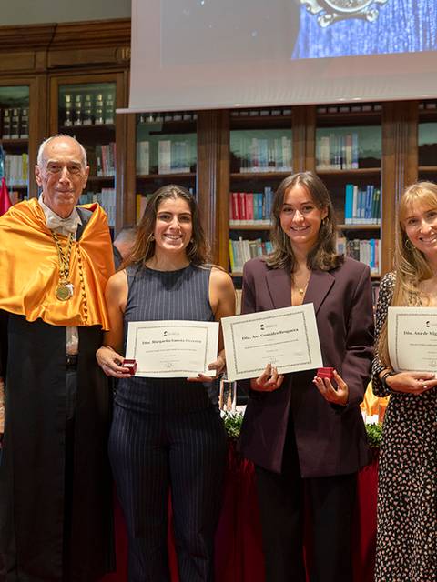 Un acto académico en el que se entregan certificados a tres mujeres destacadas en un ambiente ceremonial.