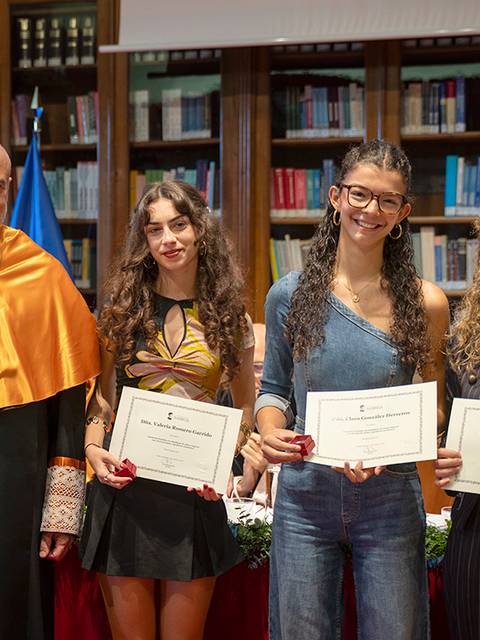 Un grupo de personas en un evento de entrega de premios, mostrando sus certificados con orgullo.