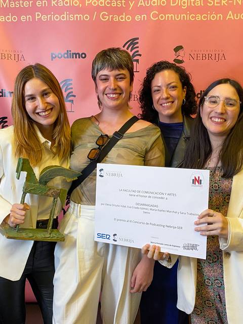 Cuatro personas sonrientes posan con un premio en un evento relacionado con el periodismo y la comunicación.