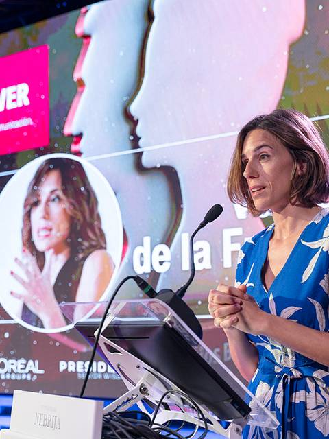 Una mujer está en un escenario presentando un premio en un evento formal.