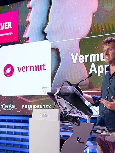 Un hombre está presentando un premio en un evento relacionado con la comunicación y la creatividad.