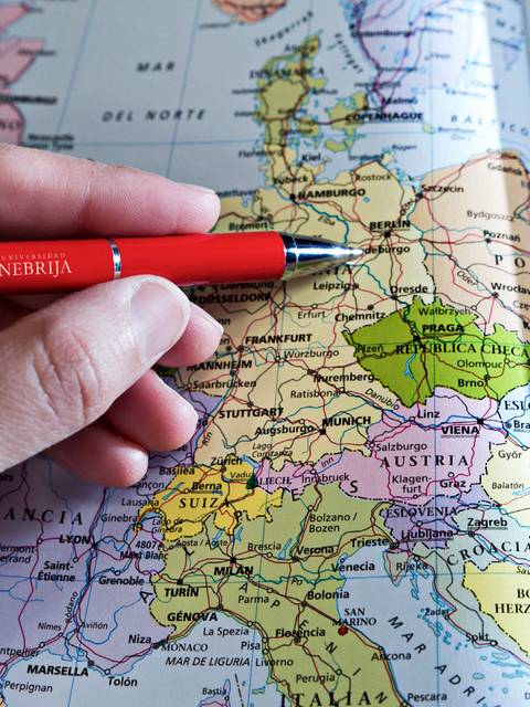 Una mano sostiene un bolígrafo rojo sobre un mapa de Europa.