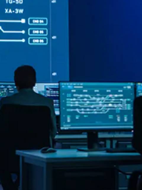 La imagen muestra a varias personas en un entorno de oficina digital frente a pantallas con datos y gráficos tecnológicos.