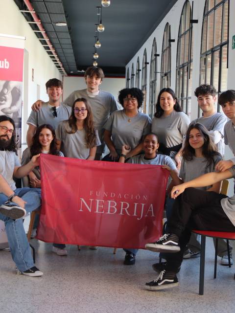 Un grupo de jóvenes posan juntos en un pasillo con una bandera de la Fundación Nebrija y un banner de CineClub.