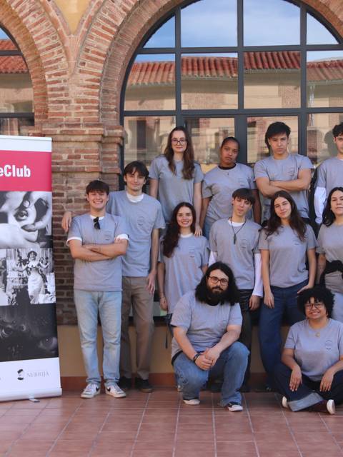 Grupo de jóvenes posando frente a un cartel de CineClub en un ambiente al aire libre.