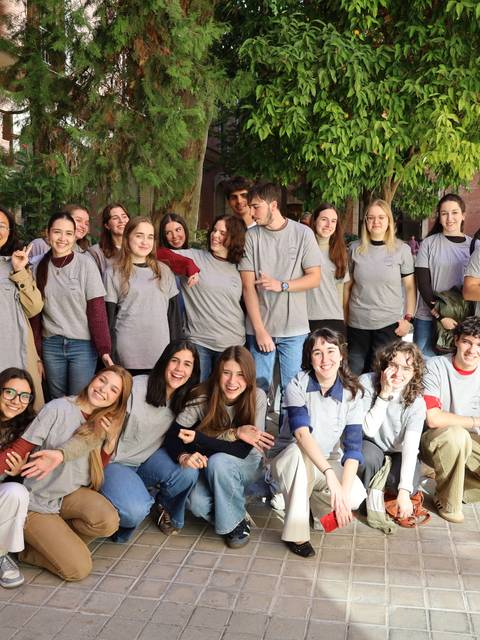 Grupo de personas sonrientes vistiendo camisetas grises en un evento del Club de Diseño.
