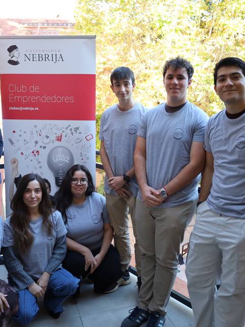 Un grupo de personas posa frente a un cartel del Club de Emprendedores de la Universidad Nebrija.