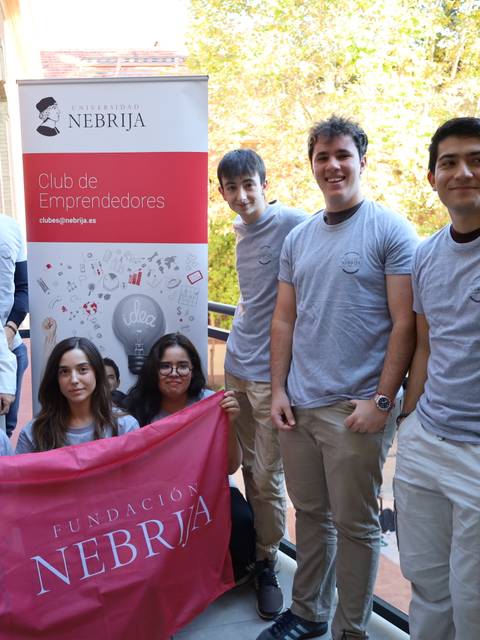 Grupo de jóvenes posando con una bandera y un cartel del Club de Emprendedores de la Fundación Nebrija.
