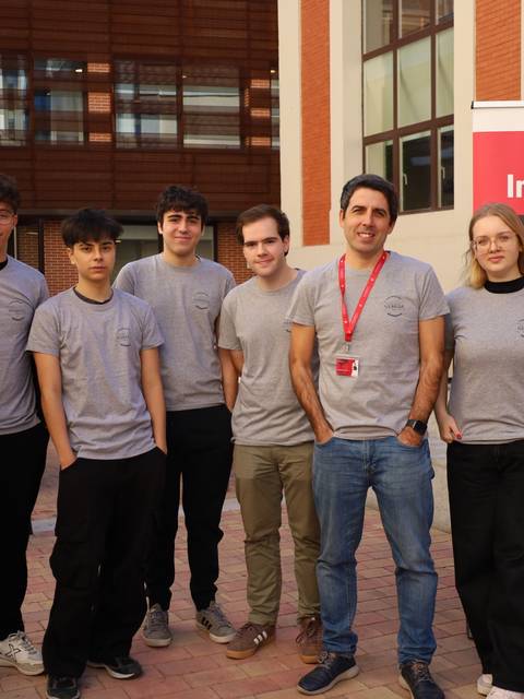 Grupo de estudiantes de un club de informática posando juntos frente a un cartel.