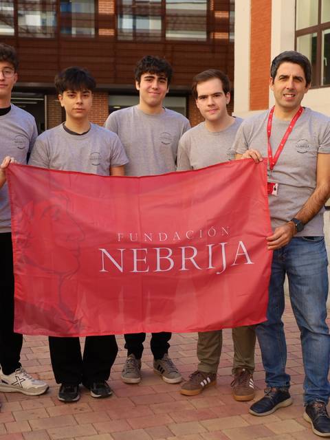 Un grupo de estudiantes y un educador sosteniendo una bandera de la Fundación Nebrija.