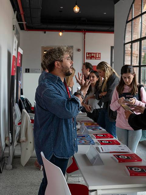 Una exposición de un festival internacional donde varias personas interactúan en un ambiente creativo.