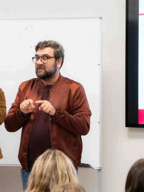 Dos hombres están presentando en un laboratorio de actualidad frente a un grupo de personas.