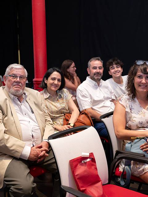 Un grupo de personas sentadas en un auditorio durante un evento.