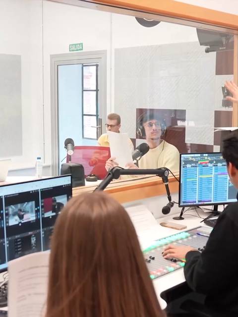 Un grupo de estudiantes está trabajando en un estudio de grabación con monitores y equipos de sonido.