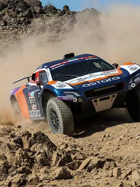 Un vehículo de carreras atraviesa un terreno rocoso y polvoriento.