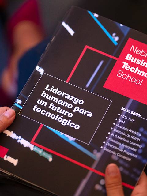 Una persona sostiene un folleto de la Nebrija Business & Technology School que habla sobre liderazgo humano y futuro tecnológico.