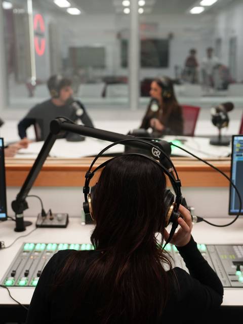 Un grupo de personas interactúa en un estudio de grabación de radio.