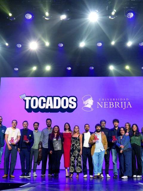 Un grupo de personas posando en un escenario con un fondo que presenta un evento relacionado con la Universidad de Nebrija.