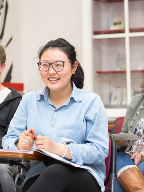 Un grupo de estudiantes sonrientes asisten a una clase en un aula.