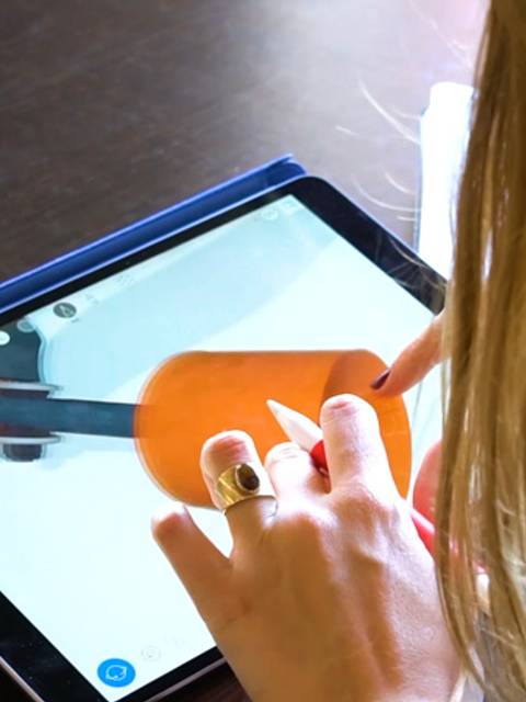 Una persona utiliza una tablet para interactuar con una aplicación que muestra un objeto en 3D.