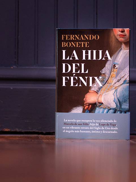 La imagen muestra el libro 'La hija del fénix' de Fernando Bonete apoyado sobre un suelo de madera.