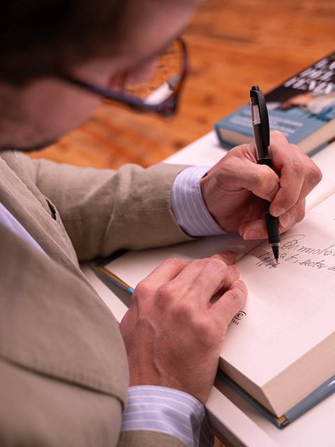 Un hombre está firmando un libro en una mesa.