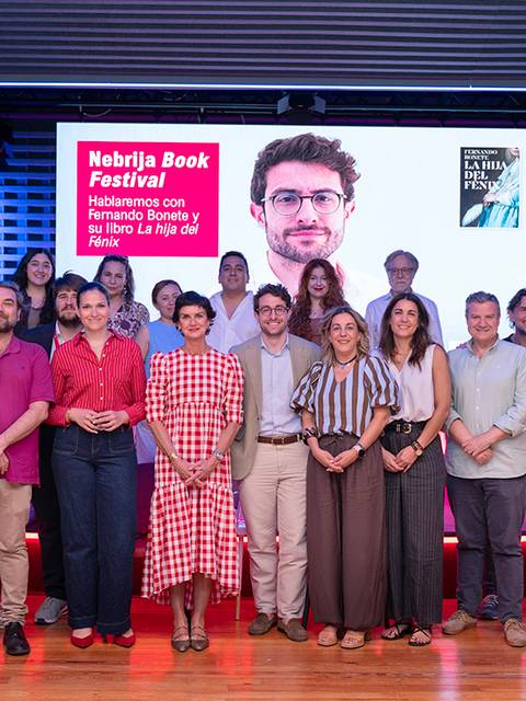 Un grupo de personas posa en un evento del Festival del Libro Nebrija, con una pantalla promocional al fondo.