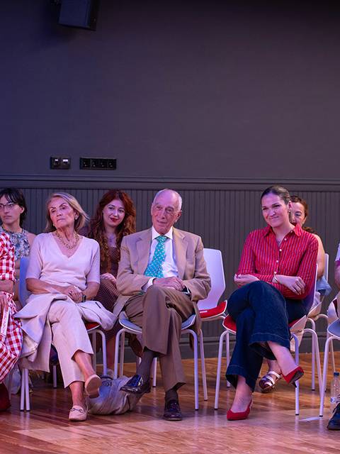 Un grupo de personas sentadas en un evento, mostrando diversas expresiones y estilos de vestimenta.