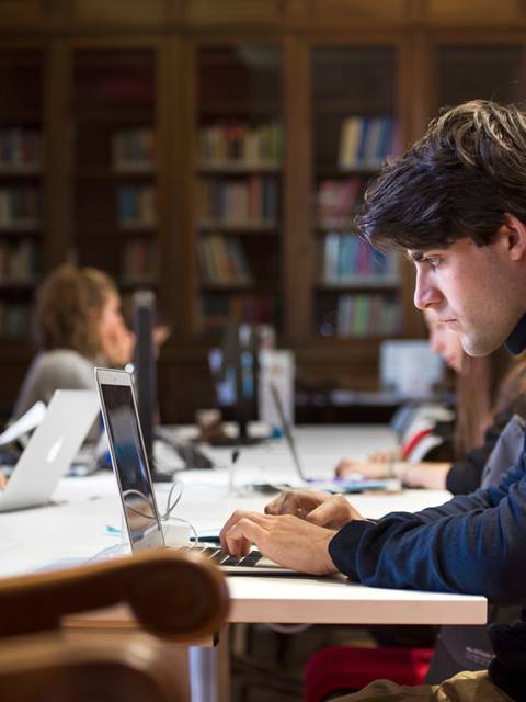 Un grupo de estudiantes trabajando en computadoras portátiles en una biblioteca.