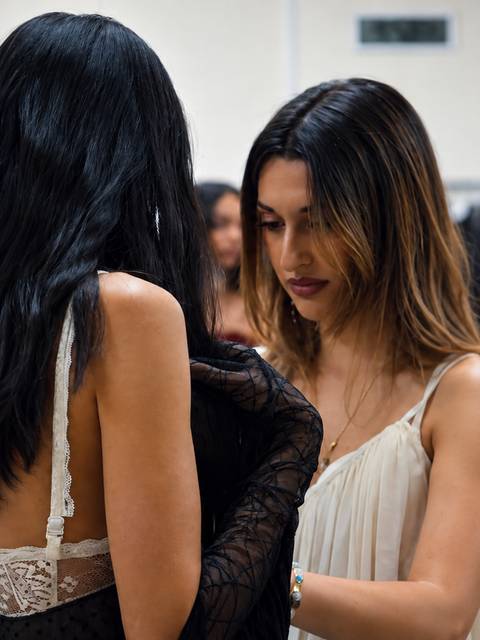 Dos mujeres se ayudan a vestirse en un ambiente de moda.